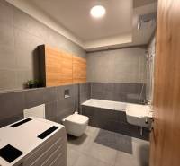 Koupelna v 2-pokojovém bytě s vanou, umyvadlem, závěsnou toaletou a skříňkami.