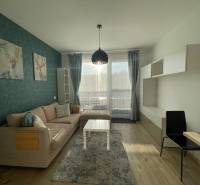 Obývací pokoj 1+kk s pohovkou, dekorací jelena a podlahou s dřevěným dekorem.