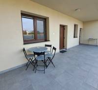 Terasa s posezením ve 4-pokojovém bytě s dlážděnou podlahou a světlými stěnami.