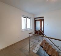 Chodba s keramickou dlažbou a schodištěm ve 4pokojovém bytě.