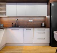 Kuchyně v 1-pokojovém bytě s podlahou s dřevěným dekorem a moderními spotřebiči.