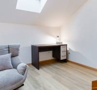 Křeslo, psací stůl a podlaha s dřevěným dekorem v 1-pokojovém bytě.