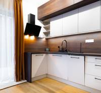 Kuchyně v 1-pokojovém bytě s podlahou s dřevěným dekorem, se závěsem a moderními spotřebiči.