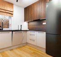 Kuchyně v 1-pokojovém bytě s podlahou s dřevěným dekorem a moderními spotřebiči.