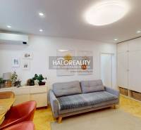 Obývací pokoj s pohovkou, jídelním stolem a podlahou s dřevěným dekorem ve 3pokojovém bytě.