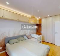 Ložnice v 3-pokojovém bytě s vestavěnými skříněmi, postelí a postýlkou.