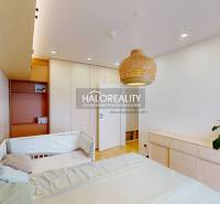 Dětský pokoj s postelí, ratanovou lampou a šatní skříní v 3-pokojovém bytě.