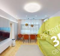 Obývací pokoj v 3-pokojovém bytě s televizí, pohovkou a dřevěným dekorem podlahy.