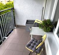 Balkon 2-pokojového bytu v Bratislavě s židlemi a zelení, vhodný k relaxaci.