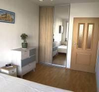 Ložnice v 2-pokojovém bytě s podlahou s dřevěným dekorem, vestavěnou skříní a komodou.