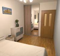 Ložnice v 2-pokojovém bytě s podlahou s dřevěným dekorem, skříně se zrcadlem a obrazem.