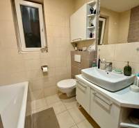 Koupelna s vanou a bílým umyvadlem v 2-pokojovém bytě.