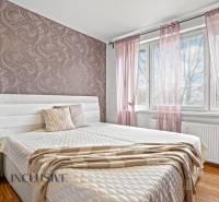 Ložnice v 3pokojovém bytě s dekorativní tapetou a podlahou s dřevěným dekorem.