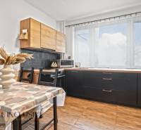 Kuchyně v 3-pokojovém bytě se světlou výzdobou a podlahou s dřevěným dekorem.