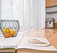 Otevřená kuchyně v 3-pokojovém bytě s dřevěným dekorem, miska s ovocem na stole.