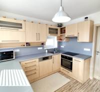 Kuchyně v rodinném domě s dřevěným dekorem a šedou pracovní deskou.