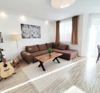 Obývací pokoj v rodinném domě s velkou sedačkou a podlahou s dřevěným dekorem.