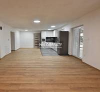 Obývací pokoj v rodinném domě s kuchyní, podlaha s dřevěným dekorem, bílé stěny.