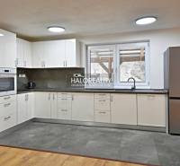 Kuchyně v rodinném domě s moderními spotřebiči a podlahou s dřevěným dekorem.