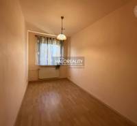 Úzký světlý prostor s oknem, závěsy a podlahou s dřevěným dekorem v 3-pokojovém bytě.