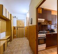 Chodba a kuchyň v 2-pokojovém bytě s dřevěným dekorem a úložnými prostory.