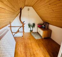 Podkrovní prostor s podlahou s dřevěným dekorem a jednoduchým nábytkem v chatě.