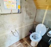 Toaleta v dřevěné chatě, s podlahou s dřevěným dekorem a oknem.