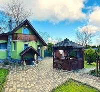 Zahradní chatka v Partizánském se zahradním altánkem a dlážděným chodníkem.