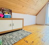 Podkroví chaty s podlahou s dřevěným dekorem, skříňkou a rostlinou.