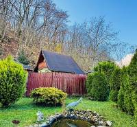 Chata v Partizánskem, obklopená zahradou s umělým jezírkem a sochami.