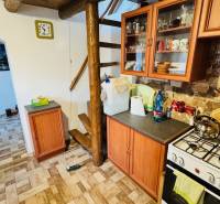 Kuchyně v chatě s dřevěným dekorem, schody, spotřebiči a nábytkem s kamennou stěnou.