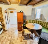 Rustikální kuchyně na chatě s plynovým sporákem a rohovou sedačkou.