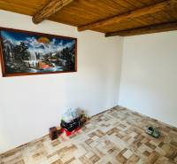 Obývací pokoj v chatě s dřevěným stropem, podlaha s dřevěným dekorem a obraz na stěně.