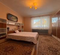 Ložnice s koberci, postelí, policemi a obrazem v rodinném domě.