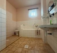 Koupelna s vanou a umyvadlem v rodinném domě s dlažbou a světlými stěnami.