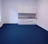 Kanceláře s bílými skříňkami a modrým kobercem ve Františkánské ulici v Trnavě.