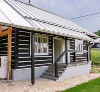 Chata v Legnavě s dřevěnou fasádou a dlážděnou terasou, obklopená zelení a přírodou.