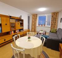 Obývací pokoj ve 4-pokojovém bytě s podlahou s dřevěným dekorem, stylovým nábytkem a jídelním stolem.