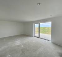 Obývací pokoj v rodinném domě s velkými okny a výhledem na zahradu.