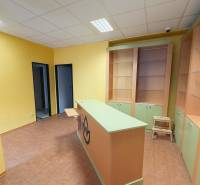 Žluté stěny, pult, regály a dlaždice v obchodních prostorách s podlahou s dřevěným dekorem.