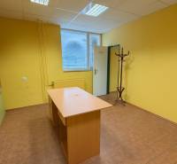 Žluté stěny kanceláře s dřevěným nábytkem, podlaha s dřevěným dekorem, věšák.