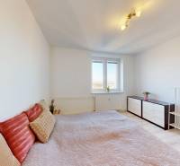 Ložnice v 3-pokojovém bytě s postelí, komodou a poličkou, podlaha s dřevěným dekorem.