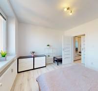 Světlá ložnice v 3-pokojovém bytě s podlahou s dřevěným dekorem a minimalistickým zařízením.