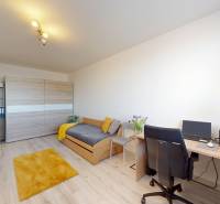 Pokoj v 3-pokojovém bytě s podlahou s dřevěným dekorem, postelí a pracovním stolem.