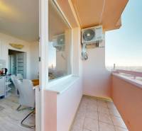 Kuchyně s jídelnou a balkonem ve 3-pokojovém bytě s podlahou s dřevěným dekorem.