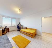 Světlý pokoj s dvěma postelemi, pracovním stolem a podlahou s dřevěným dekorem ve 3pokojovém bytě.