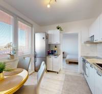 Kuchyně v 3-pokojovém bytě s jídelním stolem, podlahou s dřevěným dekorem a velkými okny.