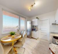 Kuchyně v 3-pokojovém bytě se světlou podlahou a jídelním stolem.