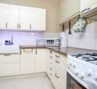 Kuchyně v 2-pokojovém bytě s rustikálními skříňkami a plynovým sporákem, světlý design.