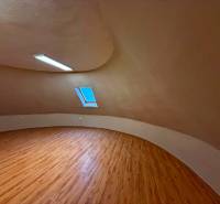 Podkroví s podlahou s dřevěným dekorem a střešním oknem v budově.